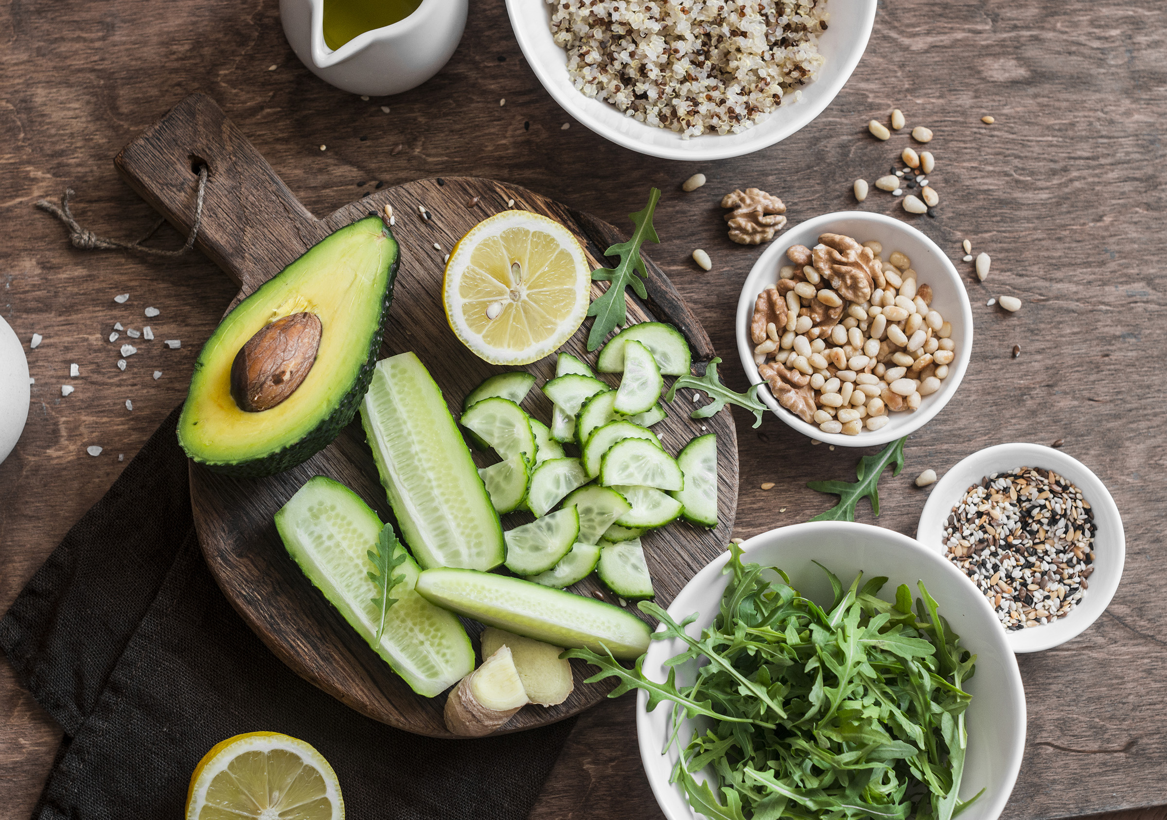 Ingredients for a spring detox salad. Quinoa, green vegetables, flax seeds, nuts, ginger. On wooden background, top view